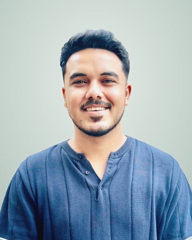 Haroon Shahbaz, founder of Integrative Rank, smiling in a navy knit shirt